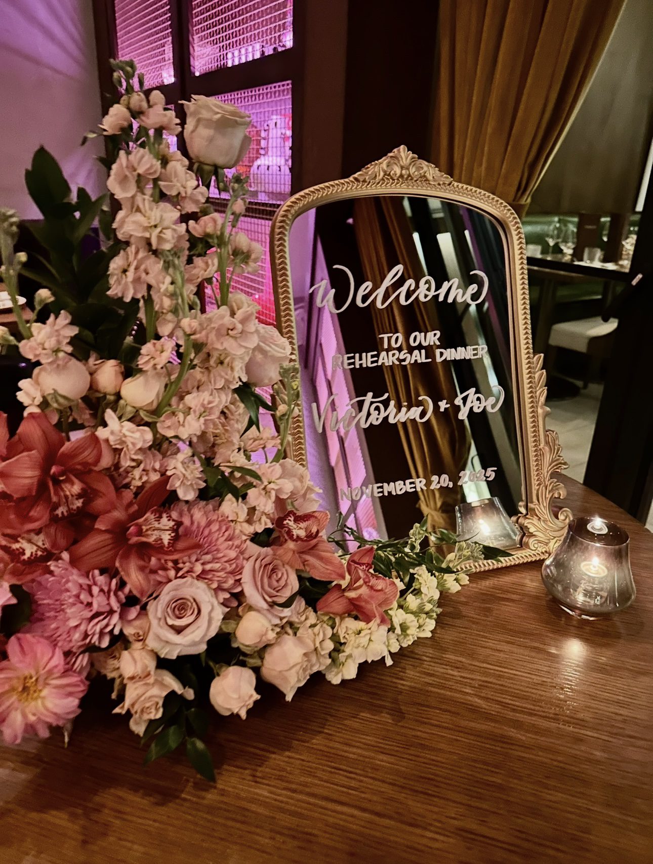 Elegant mirror welcome sign featuring custom calligraphy by Use Your Words by Nyssa for a New Jersey rehearsal dinner, surrounded by pink and white flowers.